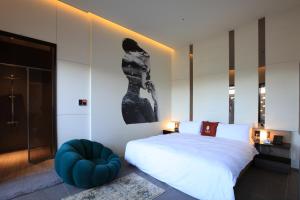 um quarto com uma grande cama branca e um repousa-pés azul em Luo Hotel em Daegu