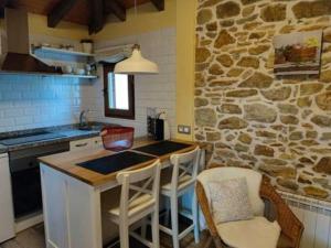 uma cozinha com uma mesa e cadeiras e uma parede de pedra em One bedroom house with shared pool terrace and wifi at Biescas em Biescas