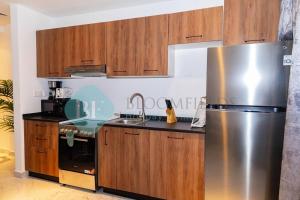 a kitchen with a stainless steel refrigerator and wooden cabinets at Luxury Studio In Oasis in Abu Dhabi