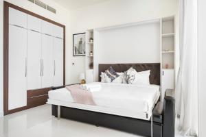 a bedroom with a large white bed with a large window at Modern Studio in Arjan-Dubailand in Dubai