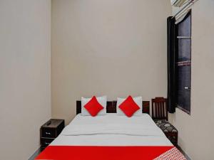 1 dormitorio con 1 cama con almohadas rojas y blancas en OYO Flagship Hare Rama Hotel en Chaukhandi
