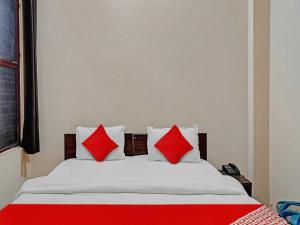 1 cama con almohadas rojas y blancas en una habitación en OYO Flagship Hare Rama Hotel en Chaukhandi