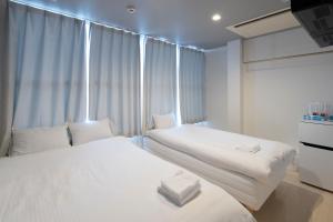 Duas camas num pequeno quarto com uma janela em Iwatoyama Hostel em Quioto