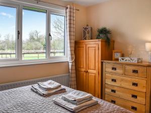 sypialnia z łóżkiem, komodą i oknem w obiekcie Willow Wood Cottage 