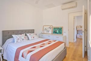 a white bedroom with a large bed and a table at Preciosa casa en el Maresme con jardín in Cabrils