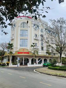 un gran edificio blanco con un coche aparcado delante de él en KHÁCH SẠN ROMO en Quang Ngai