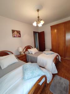 1 dormitorio con 2 camas y lámpara de araña en Casa da Rapadoira, 