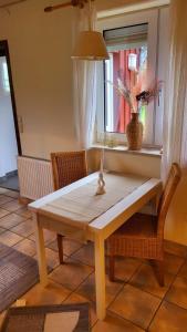 een houten tafel en stoelen in een kamer met een raam bij Burhave Gästehaus 8 in Butjadingen
