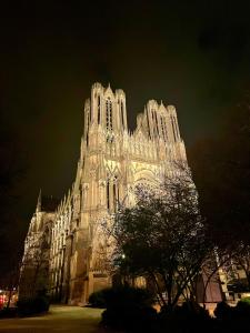 un gran edificio con luces encendidas por la noche en Champagne des Anges - Proche Cathédrale de Reims, en Reims