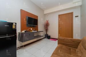 uma sala de estar com um sofá, uma televisão e uma porta em RedLiving Apartement Cinere Resort By YK rooms Tower Kintamani em Gandul
