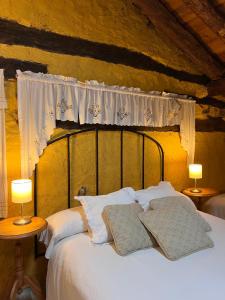 1 dormitorio con 1 cama con almohadas blancas y 2 lámparas en La casa del río, en Alameda del Valle