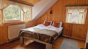 Ce lit se trouve dans un dortoir doté de murs en bois et de fenêtres. dans l'établissement Vén Fenyő Kunyhó, à Ciceu
