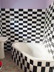a bath tub in a bathroom with black and white tiles at The Crescent Byo in Bulawayo