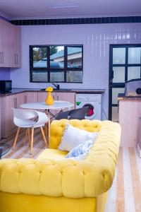 a yellow couch in a kitchen with a table at The Crescent Byo in Bulawayo