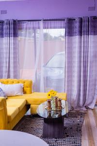 a living room with a yellow couch and a glass table at The Crescent Byo in Bulawayo