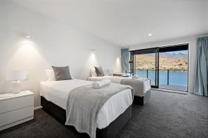 a hotel room with two beds and a large window at Luxury Lakeside Retreat in Queenstown
