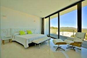 ein Schlafzimmer mit einem weißen Bett und einem großen Fenster in der Unterkunft Villa Hava - Es Cubells in San Jose de sa Talaia