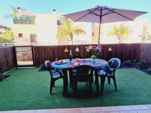 einen Tisch mit Stühlen und einen Regenschirm im Hinterhof in der Unterkunft Paraiso 2 Bedroom Terrace wifi free in Playa Paraiso