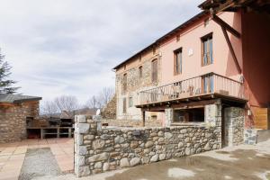 ein altes Gebäude mit einer Steinmauer und einem Balkon in der Unterkunft Masia d'en cot in Puigcerdà