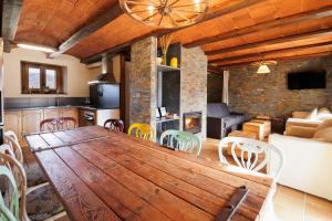 kuchnia i salon z drewnianym stołem i krzesłami w obiekcie Masia d'en cot w mieście Puigcerdà