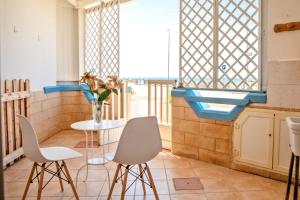a table and chairs in a room with a window at Casa Tridente - Meravigliosa villa sul mare in Torre Mozza