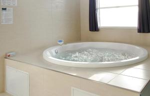 baño con bañera grande y ventana en Cozy Home In Vejers Strand With Wifi, en Vejers Strand