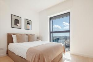a white bedroom with a large bed and a window at Nicosia Central Park Residences in Nicosia