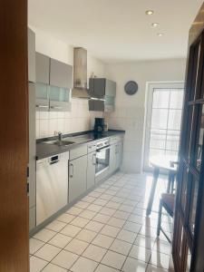 uma cozinha com electrodomésticos em aço inoxidável e piso em azulejo branco em Ferienwohnung Edental em Burgdorf