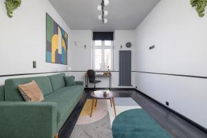 ein Wohnzimmer mit einem grünen Sofa und einem Tisch in der Unterkunft Apartment in Cracow Center with Air Conditioning, Desk and Balcony by Renters in Krakau