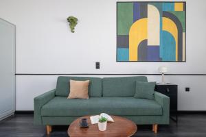 ein Wohnzimmer mit einem grünen Sofa und einem Tisch in der Unterkunft Apartment in Cracow Center with Air Conditioning, Desk and Balcony by Renters in Krakau