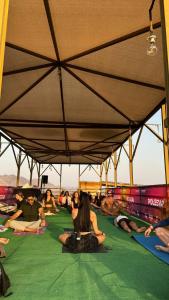 un groupe de personnes assises sur le sol sous un parapluie dans l'établissement Hatta Art Hub Farm, à Hatta