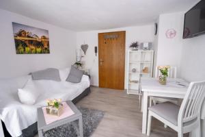 een woonkamer met een witte bank en een tafel bij Ferienwohnungen KATI in Scheidegg