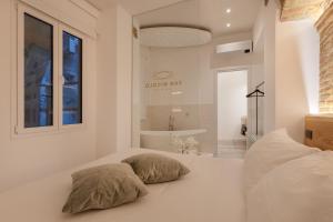 una camera bianca con due cuscini su un letto di San Nicolò Suites a Trieste