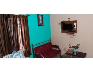 Cette petite chambre comprend un canapé rouge et une table. dans l'établissement Venus Hotel, New Digha, WB, à Digha