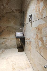 a bathroom with a toilet on a stone wall at SEVEN HILLS Guest House in Akalkot