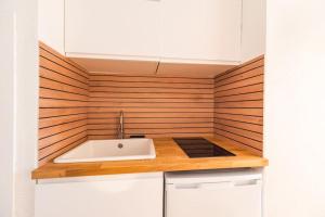 a kitchen with a sink and a wooden wall at Le studio briochin - Saint-Brieuc in Saint-Brieuc