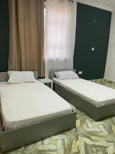 two twin beds in a room with at Serene Hostel in Aboman