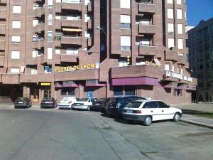 un estacionamiento con autos estacionados frente a un edificio en Apartamentos Turisticos Puerta de León, en León