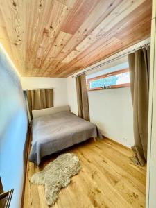 una piccola camera con letto e soffitto in legno di Appartement Rosa au coeur des 4 Vallées a Conthey