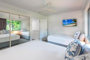 a bedroom with two beds and a mirror at Sunset Waters Apartments in Hamilton Island