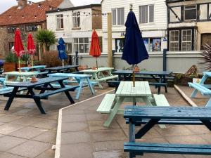 a group of picnic tables with an umbrella at The Lobster in Sheringham