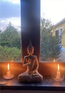 a statue sitting in front of a window with candles at Quinta Cunte - Casa Girassol in São Luis