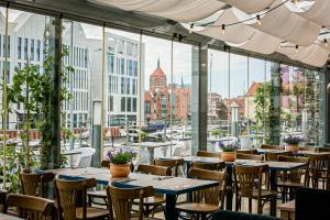 un restaurante con mesas y sillas y vistas a la ciudad en Hostel Gdańsk Szafarnia 10 Old Town, en Gdansk