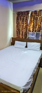 łóżko z białą pościelą i poduszkami w pokoju w obiekcie Hotel JM International (A Unit of Hotel Care Plaza) w mieście Puri