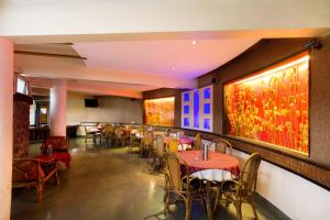 un restaurante con mesas, sillas y pinturas en las paredes en Treebo Trend Niraali Executive en Pune