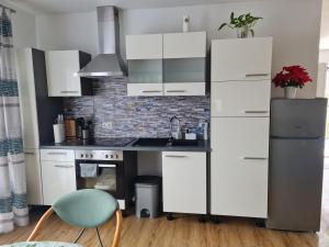 a kitchen with white cabinets and a green chair at Ferienwohnung Traisen Has in Traisen