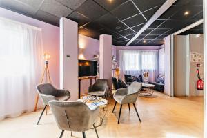 デシーヌ・シャルピューにあるThe Originals City, Hôtel Éclipse, Lyon Est (Inter-Hotel)の椅子とテーブルが備わる客室です。