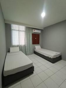 a room with two beds and a window in it at Hotel Iramanis in Lahad Datu