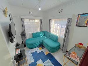 a living room with a blue couch and a tv at Homely apt 1 (one) in Kisumu