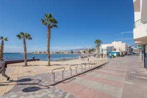 una persona caminando por una acera junto a una playa en Lightbooking Apartamento con terraza en playa de Arinaga, en Agüimes